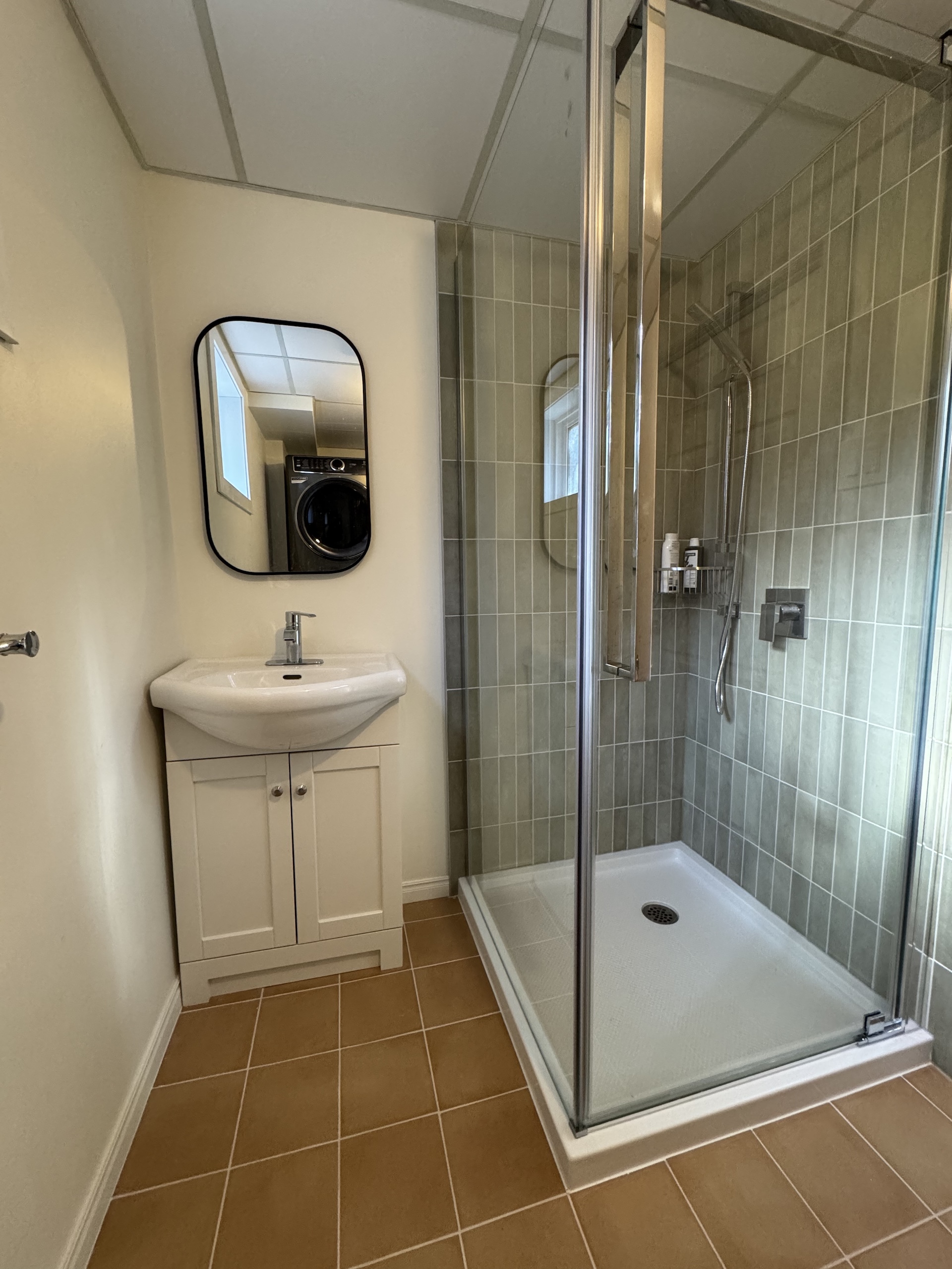 Trendy green vertical subway tile installation in glass shower enclosure