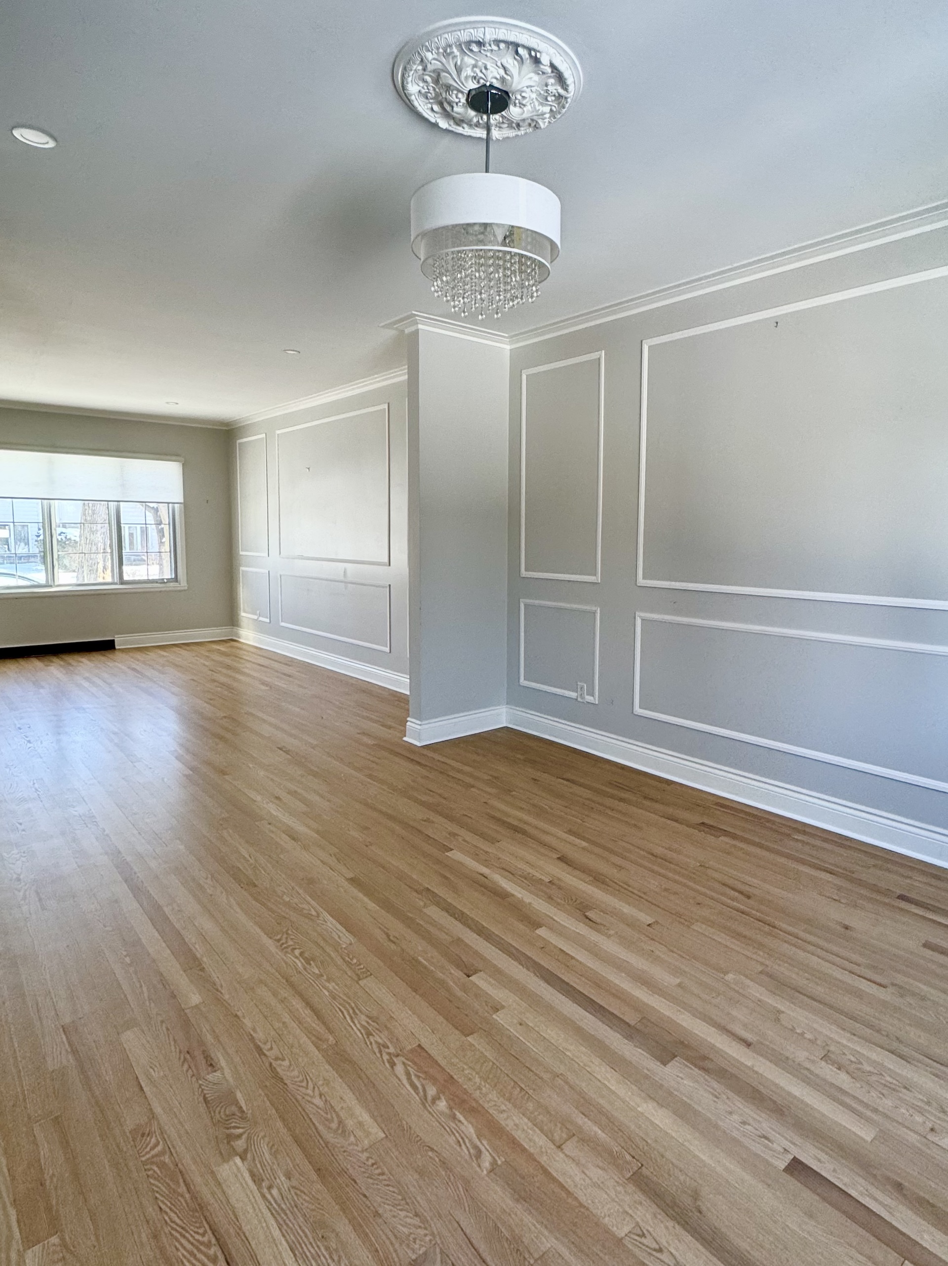 Refinished natural hardwood floors in formal living room with wainscoting