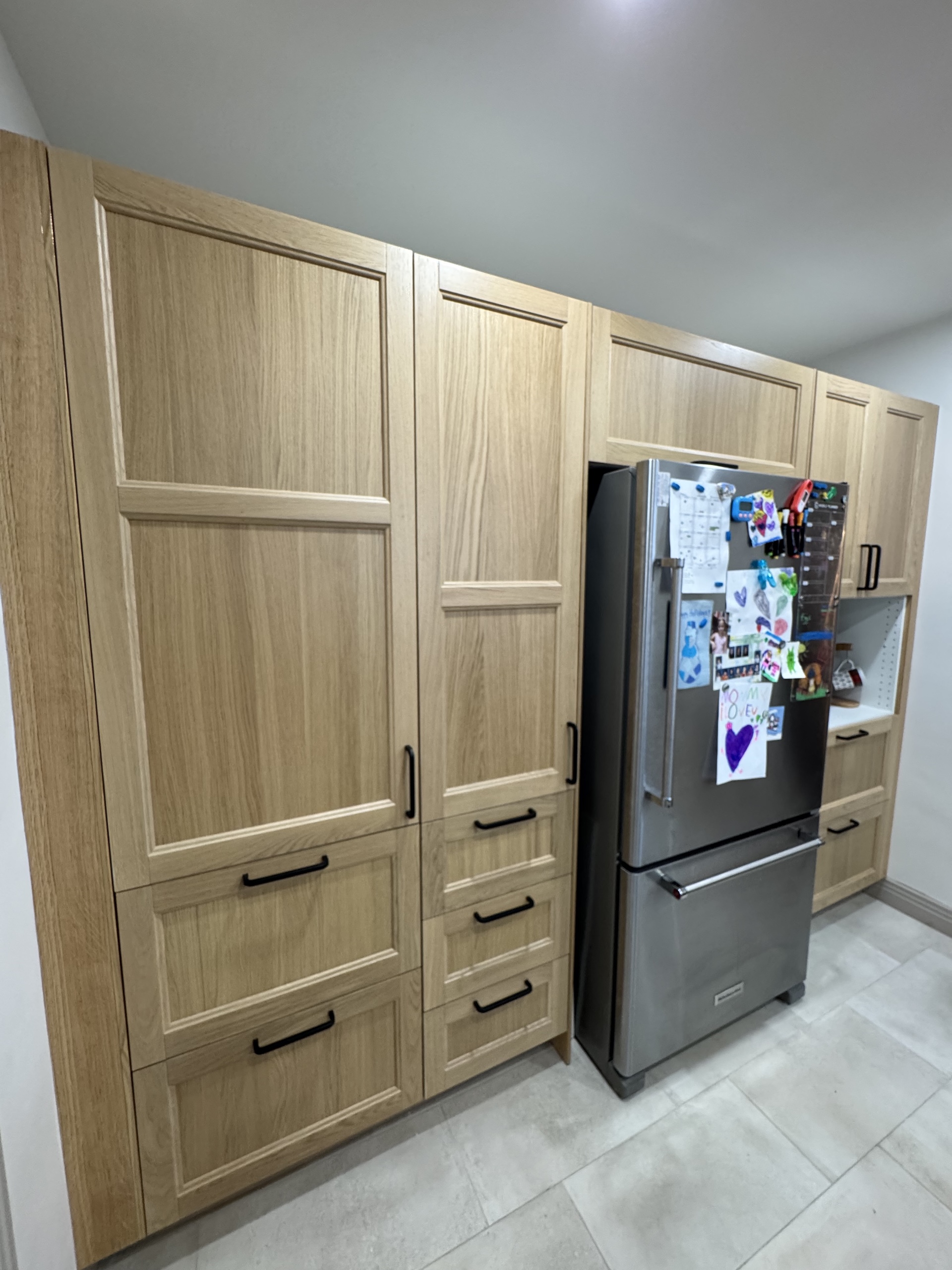 Custom floor-to-ceiling white oak pantry cabinets with integrated fridge