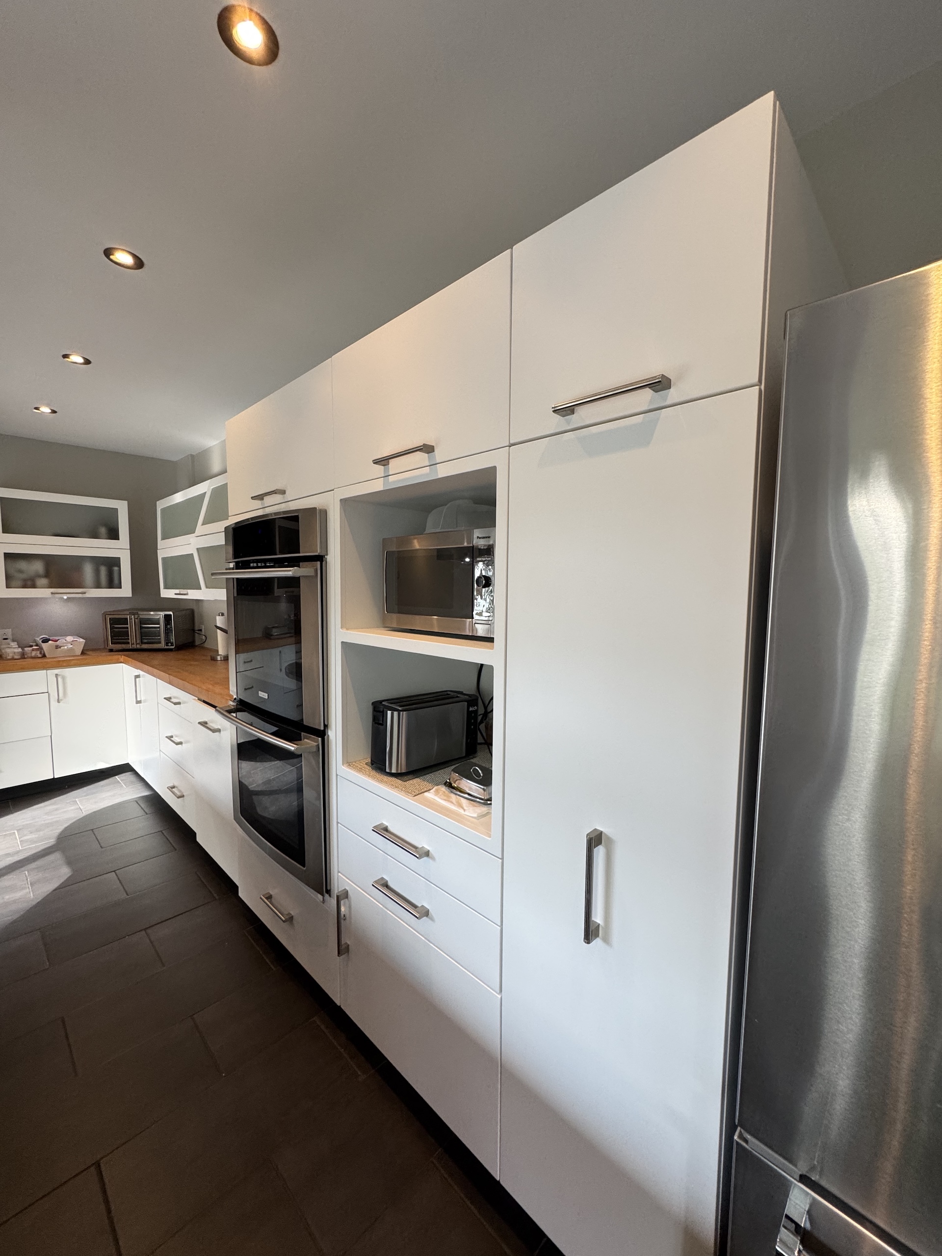 Modern white kitchen cabinetry wall with integrated microwave and oven appliances