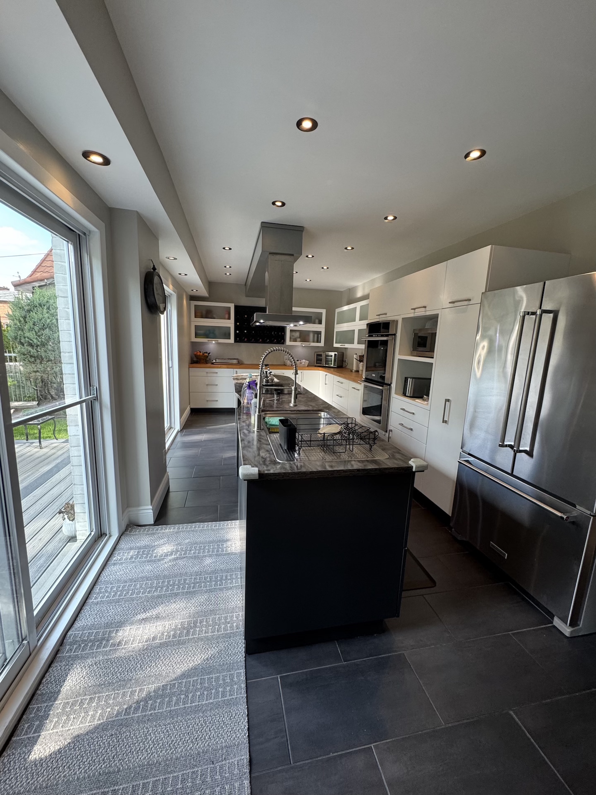 Spacious open concept kitchen renovation with large black island and patio access