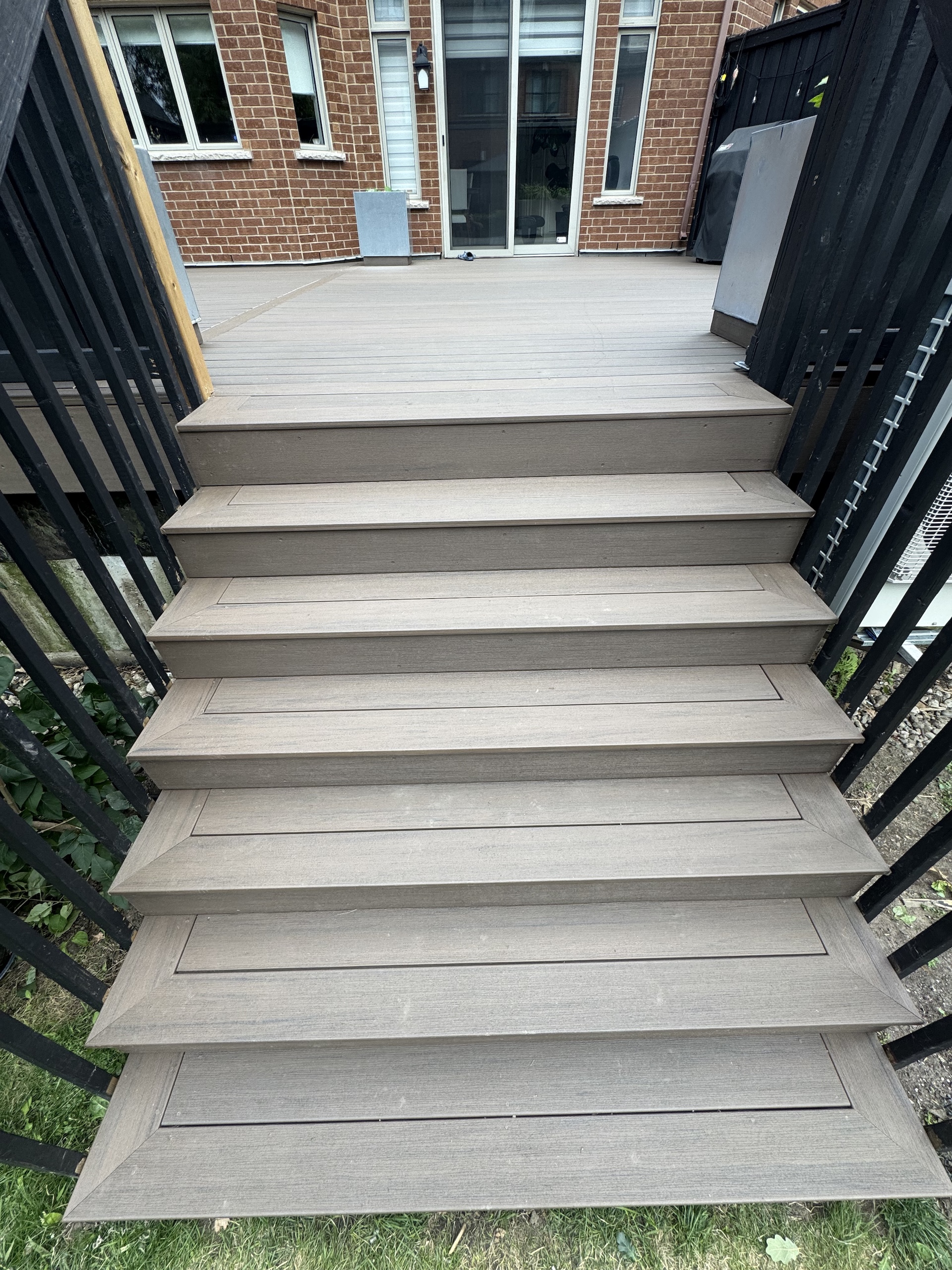 High-end deck construction detail showing wide composite steps with picture-frame bordering